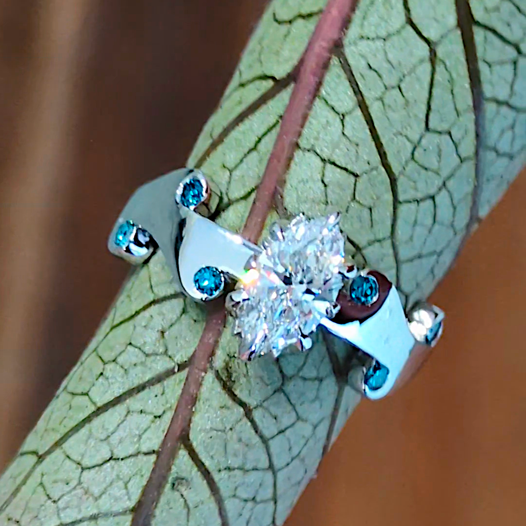 designer diamond ring set with a large marquise diamond and small blue diamonds in a fire design by Christine Sadler