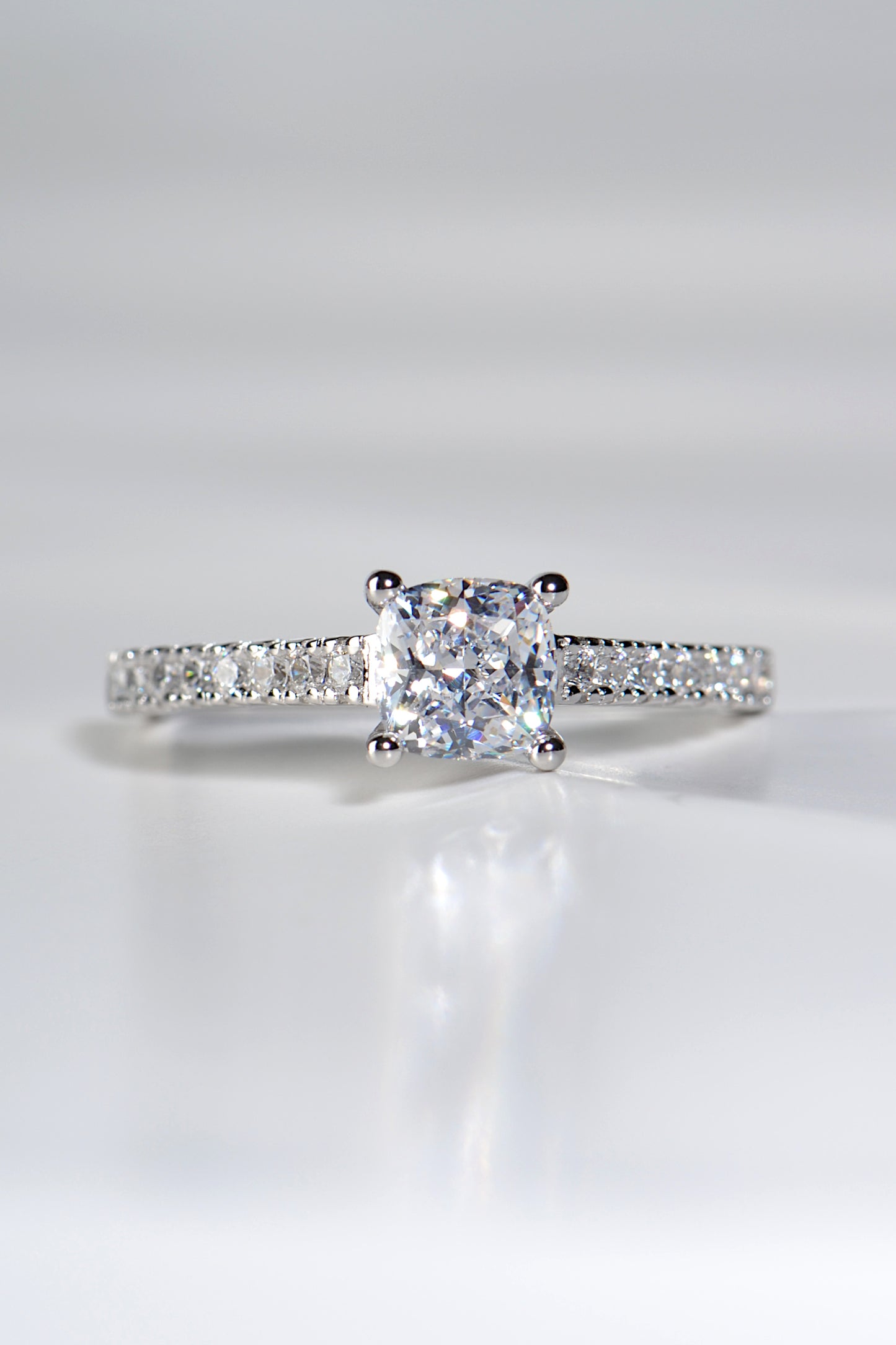 cushion cut platinum diamond engagement ring with diamonds in the shoulders made in the UK