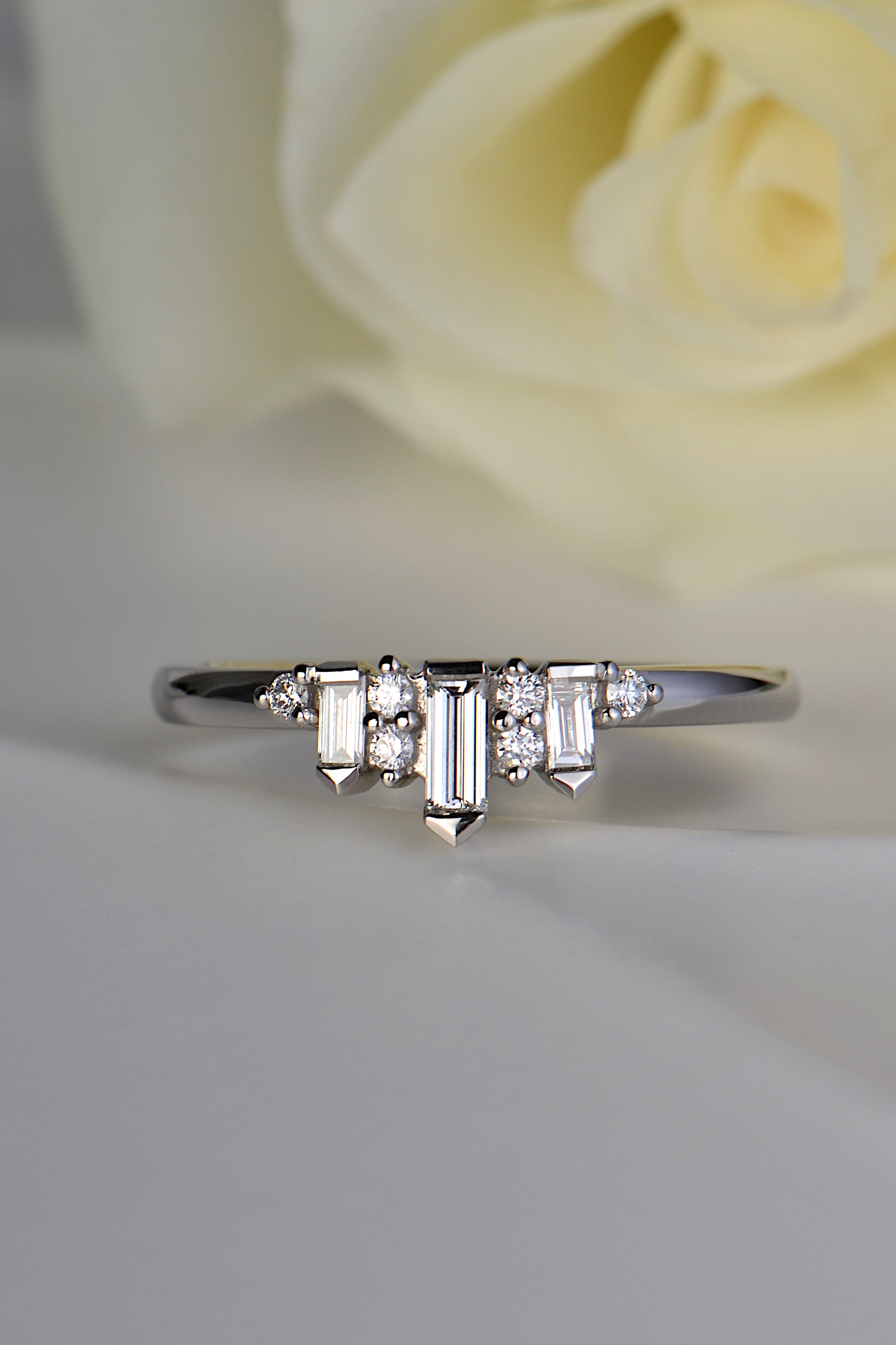 decorative diamond and platinum ring with three baguette diamonds spaced out by two pairs of round brilliant cut diamonds with a round diamond at each end.