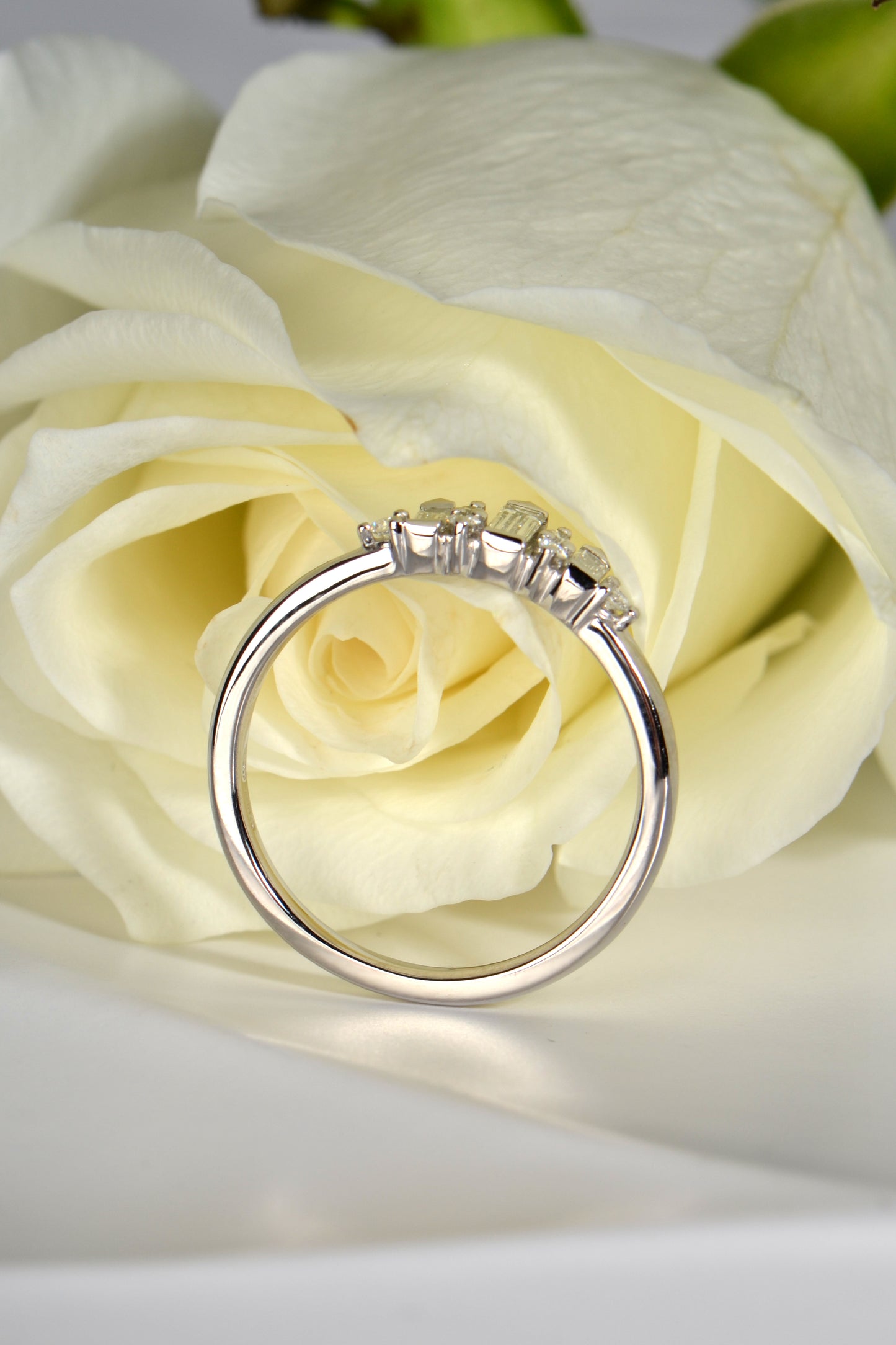 high quality British platinum and diamond ring with a white rose in the background