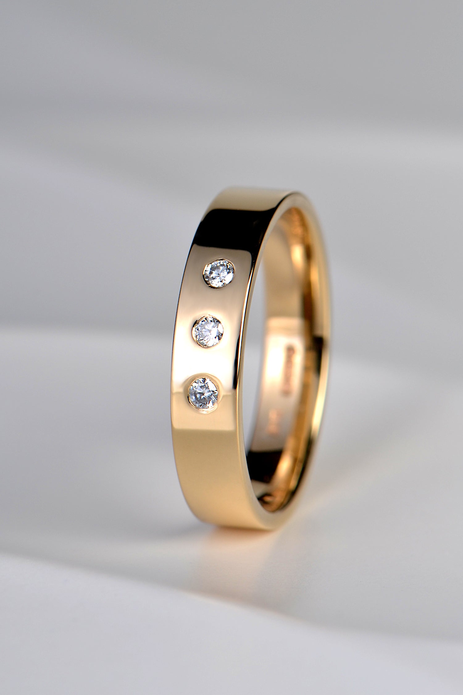 modern yellow gold wedding ring set with three round diamonds at the front