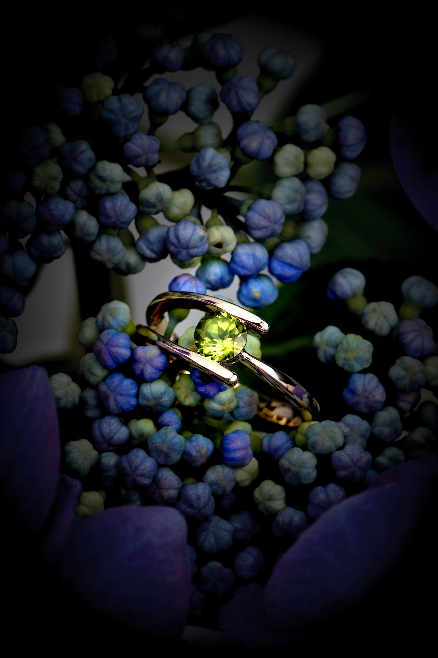 peridot and yellow gold asymmetric ring by jewellery designer Christine Sadler photographed on blue Hydrangea flowers