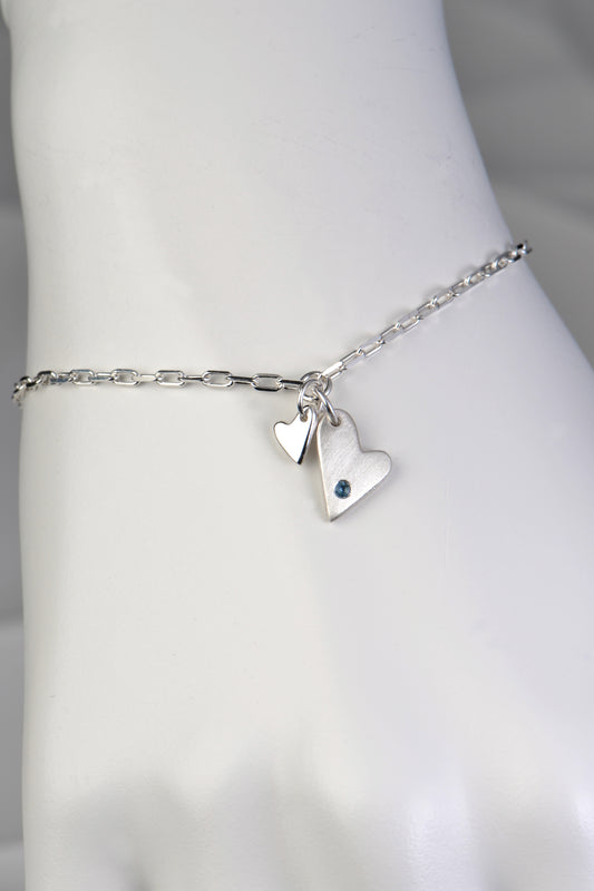 silver designer bracelet with a two hearts, one small polished heart and one large matt finished heart set with an aquamarine birthstone - Christine Sadler