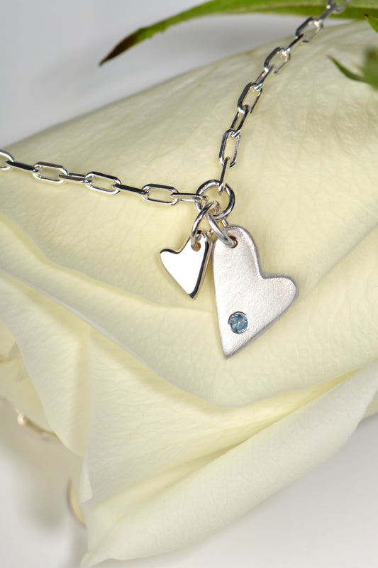 two heart silver bracelet set with an aquamarine gemstone on a white rose - Christine Sadler